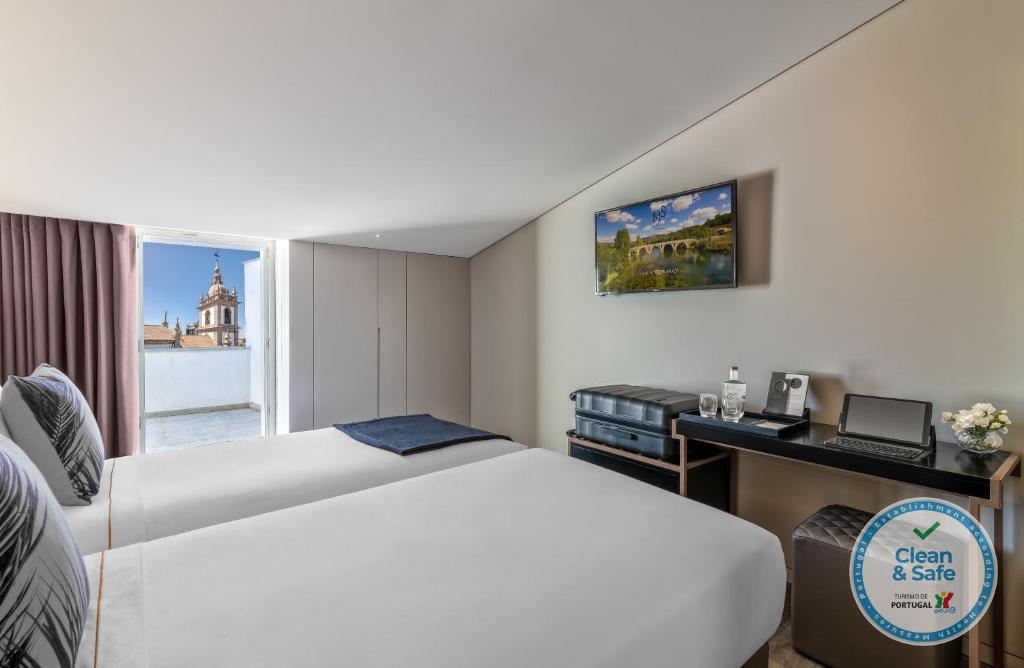 布拉加Hotel Moon & Sun Braga的配有一张床、一张书桌和一扇窗户的酒店客房