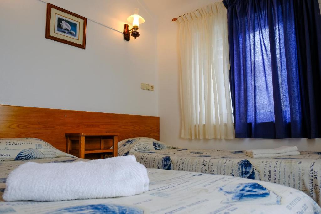 佩尼契Rimavier Residence的一间卧室设有两张床,窗户配有蓝色窗帘