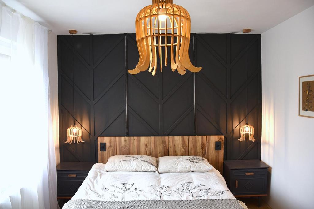 VisokoLesnavesna designer Apartment with a garden的一间卧室配有一张大床和一个吊灯。