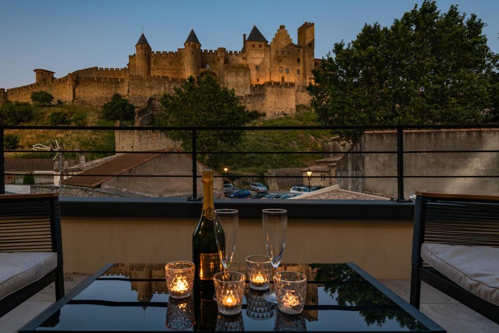 卡尔卡松Le Loft de La Tour Pinte的城堡阳台的桌子上摆放着一瓶葡萄酒