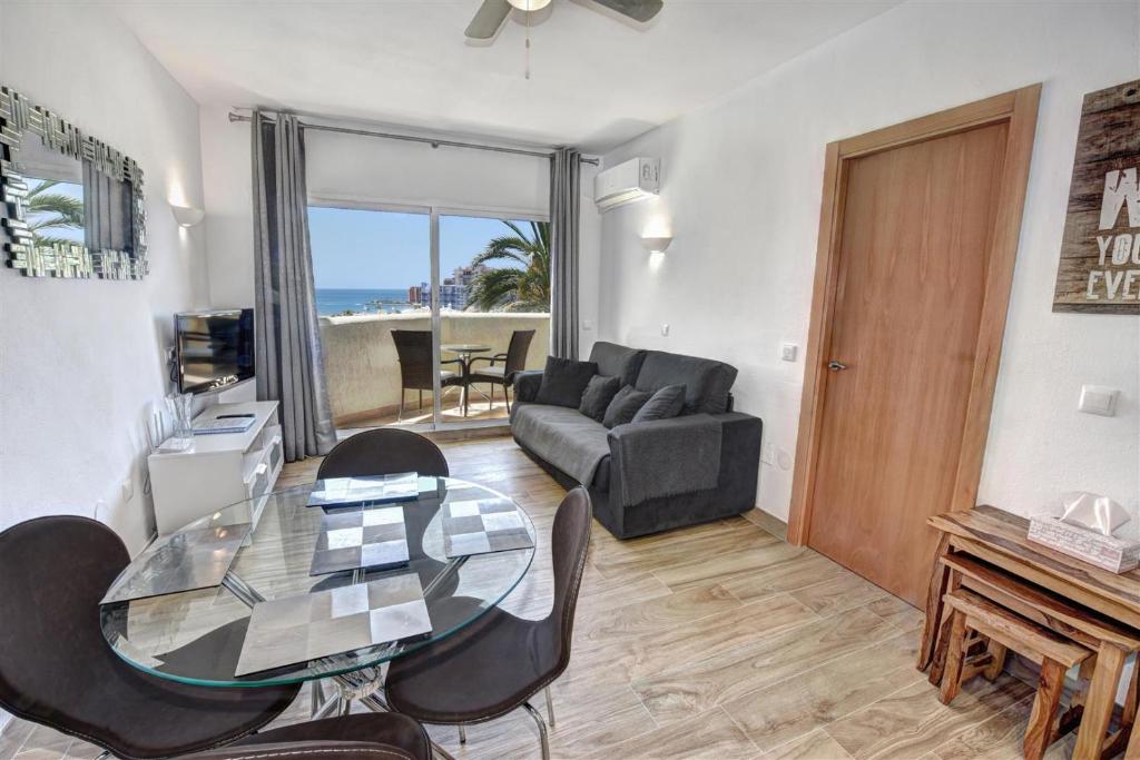 贝纳尔马德纳Benal Beach, Luxury Sea & Mountain View Beachside 1 Bedroom Apartment的客厅配有玻璃桌和椅子