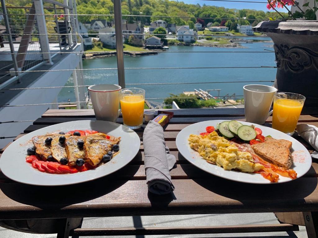 布斯贝港Harborage Inn on the Oceanfront的桌上放两盘食物,享有水景