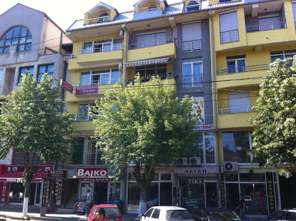 斯特鲁加Hotel Venecia Apartments的一座黄色的建筑,前面有汽车停放