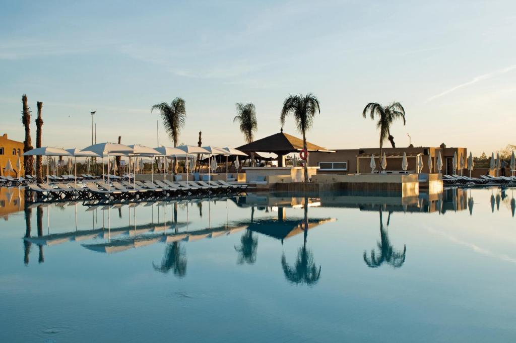 马拉喀什Hotel Riu Tikida Palmeraie - All Inclusive的一个带椅子和棕榈树的游泳池