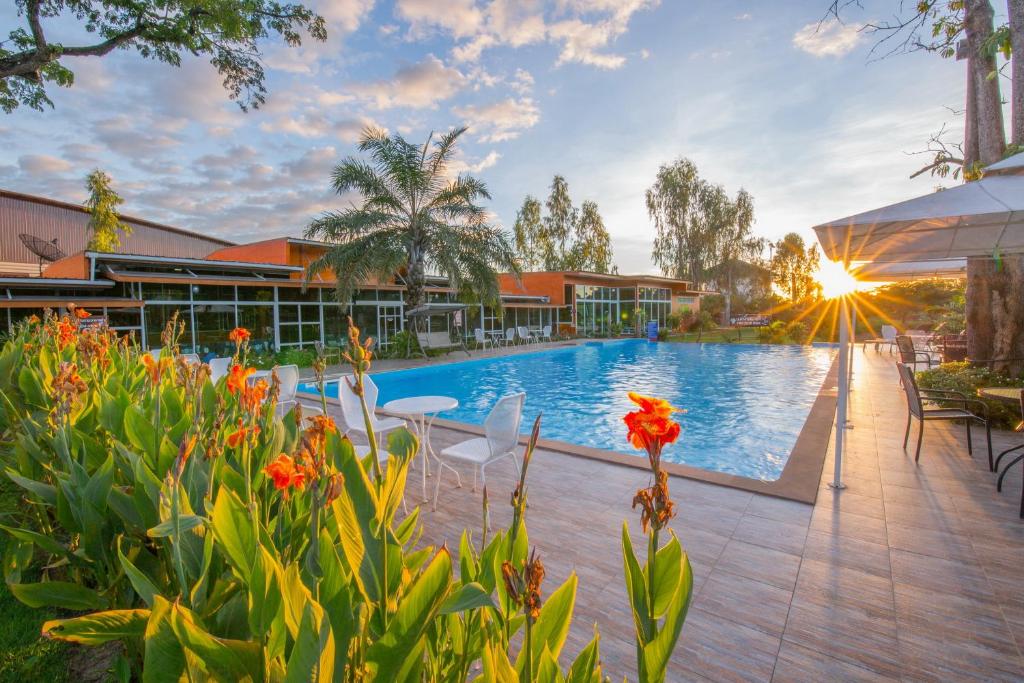 乌汶班萱坤塔高尔夫度假酒店的一座建筑前带椅子和鲜花的游泳池