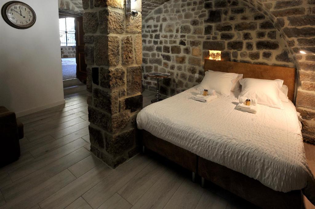 SanilhacChambre Comballe charmante avec jacuzzi的卧室配有砖墙内的床铺