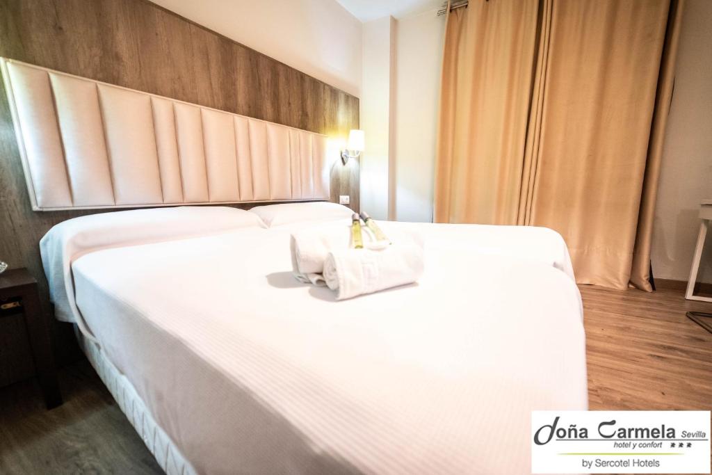 塞维利亚塞尔科蒂尔多纳卡梅拉酒店的一张白色的大床,带两条毛巾
