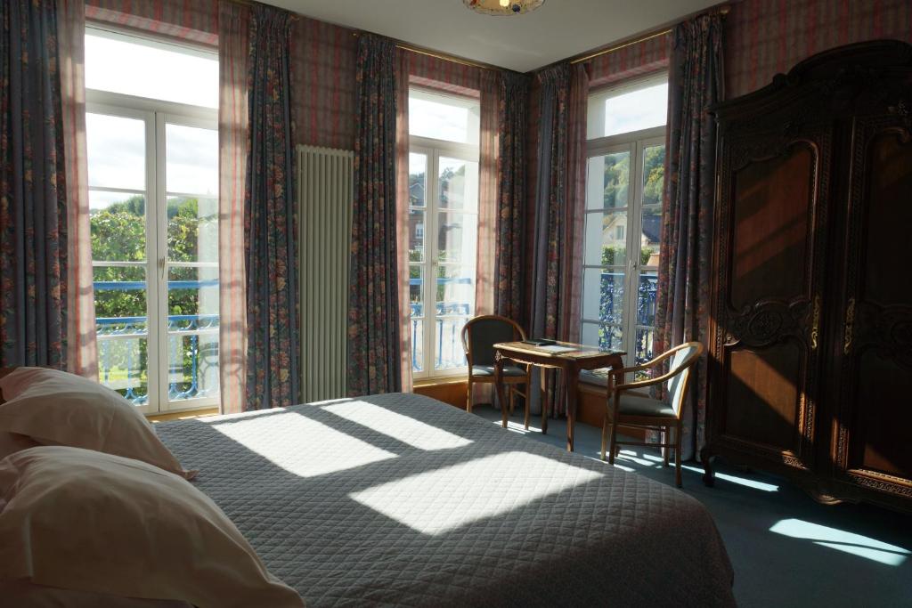 翁弗勒尔勤勉酒店的一间卧室配有一张床、椅子和窗户。