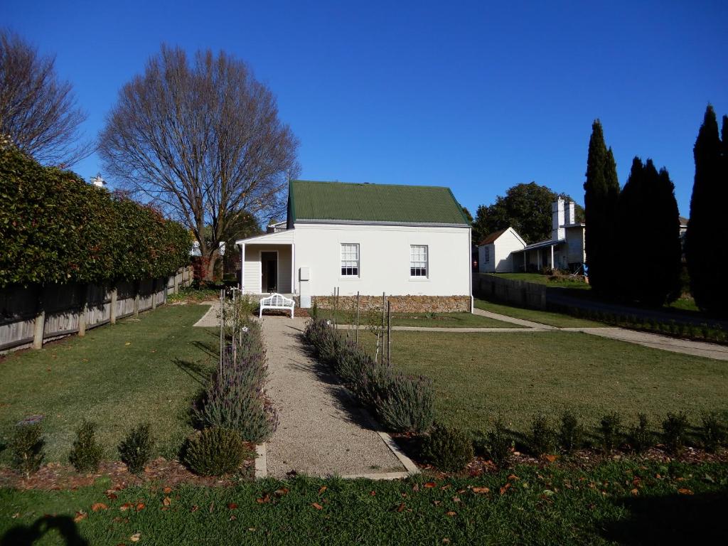 德洛兰The Chapel Deloraine的院子里的白色房子,有绿色屋顶