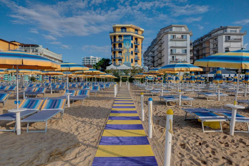 利多迪耶索罗拿破仑酒店的海滩上摆放着蓝色和黄色的椅子和遮阳伞