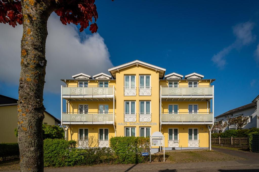 奥斯特巴德·哥伦豪斯索能斯海恩海伦酒店的黄色的建筑,带有白色的阳台和树