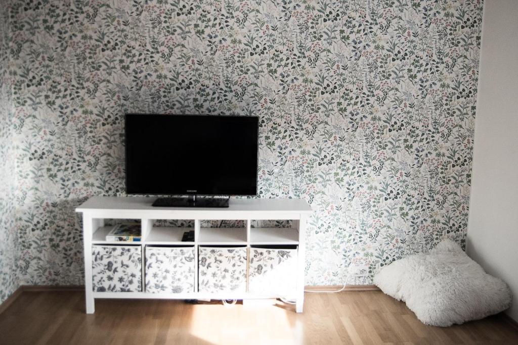 哈普萨卢Põllupesa的客厅的墙上设有电视,墙上装饰有花卉图案的壁纸