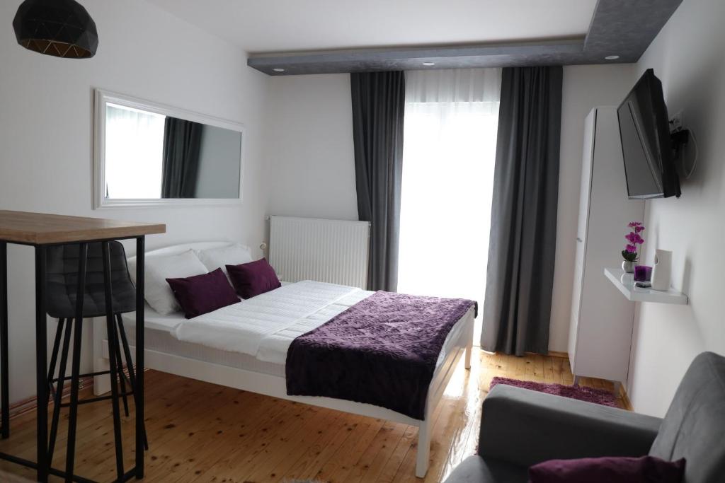 新瓦罗什Apartman Ena的一间卧室配有一张带紫色床单的床和窗户。