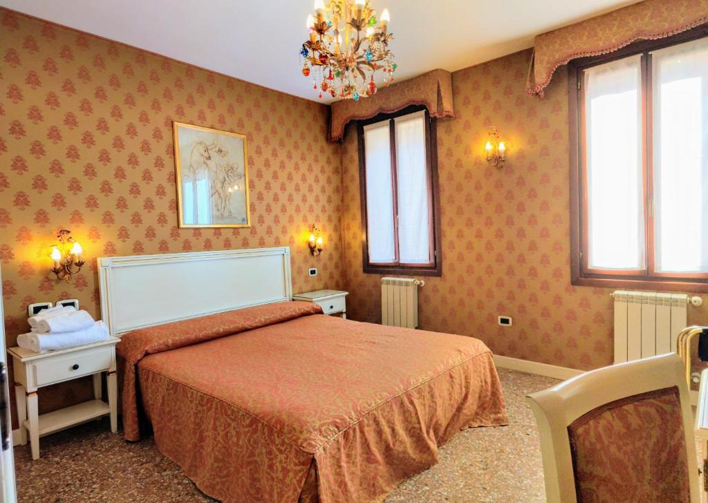威尼斯卡圣比欧酒店的一间卧室配有带橙色床单和窗户的床。