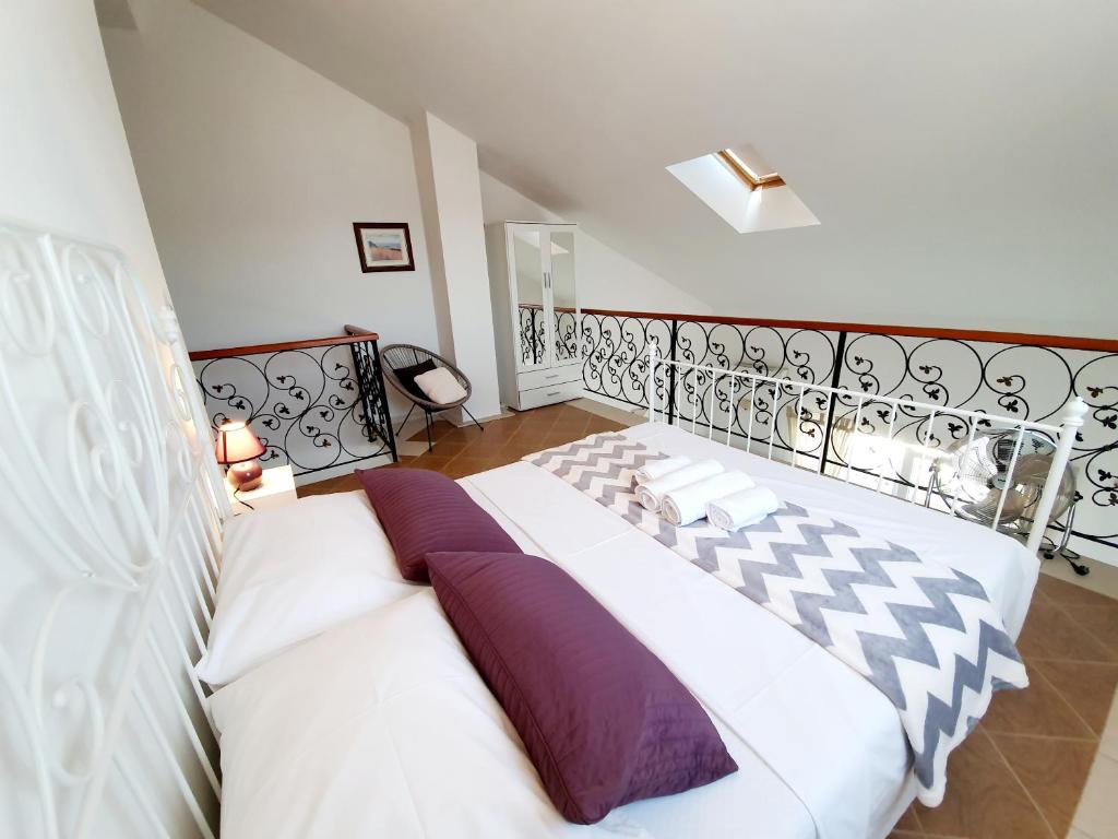 塞维德Apartmani Mikulić的卧室配有一张带紫色枕头的大型白色床。
