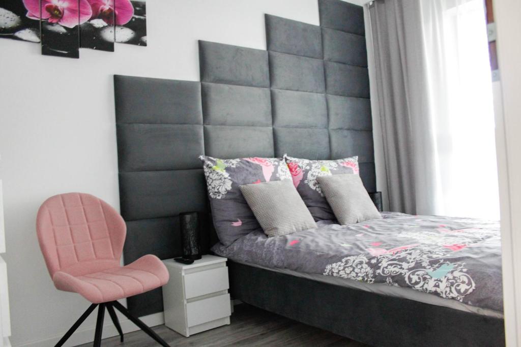 弗罗茨瓦夫Apartament Wrocław Centrum Galeria Magnolia的一间卧室设有大型床头板和粉红色的椅子