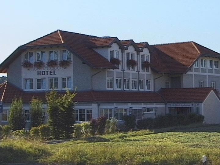 登肯多夫施图本-莫扎特酒店的一座大型建筑,在田野顶部设有酒店