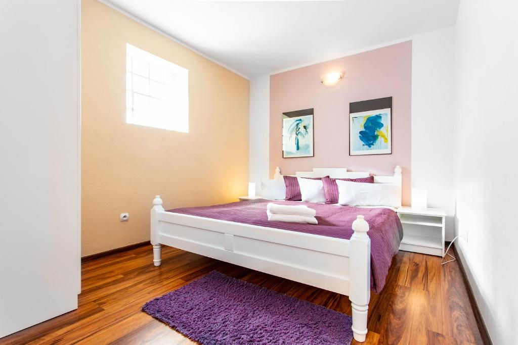 尤斯托尼莫斯基Plaża Apartament的卧室配有白色床、紫色床单和窗户