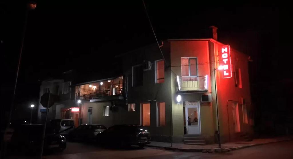 Byala SlatinaСемеен хотел Лъки的一座红色的建筑,晚上有 ⁇ 虹灯标志