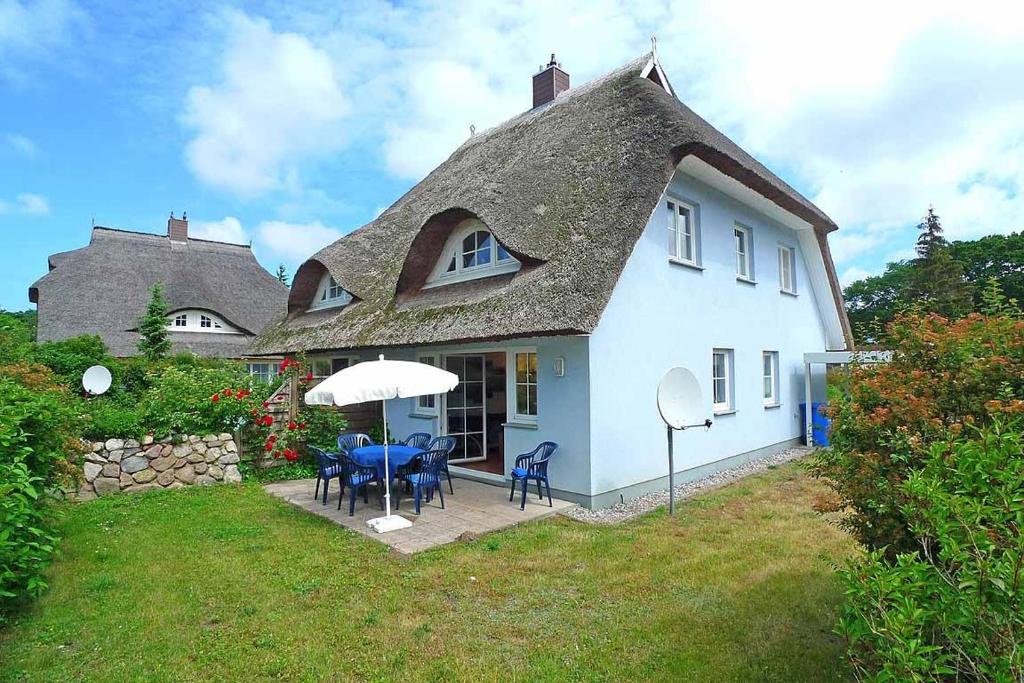 博恩Ferienhaus das Blaue Haus WS-9a的白色的房子,配有桌椅和遮阳伞