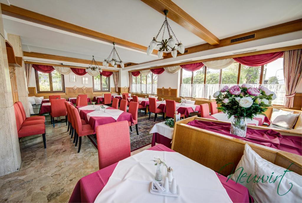 克拉根福Gasthof Neuwirt / Kressnig的餐厅设有桌子和红色椅子,并种植了鲜花。