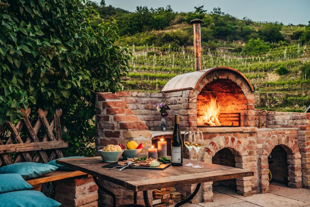 杜伦斯坦Wachau-Living的石头比萨饼烤箱,桌子上放着食物和葡萄酒
