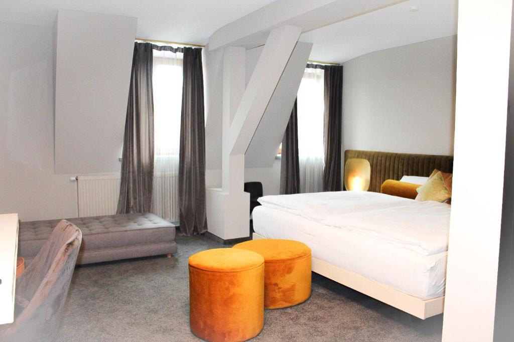 克伦巴赫Hotel Krumbach的一间卧室配有一张床和两张橙色凳子