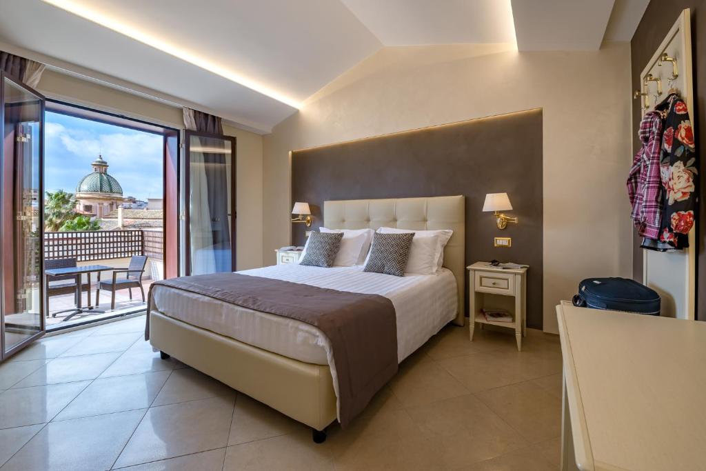 夏卡Vittorio Emanuele Boutique Hotel的一间带大床的卧室和一个阳台