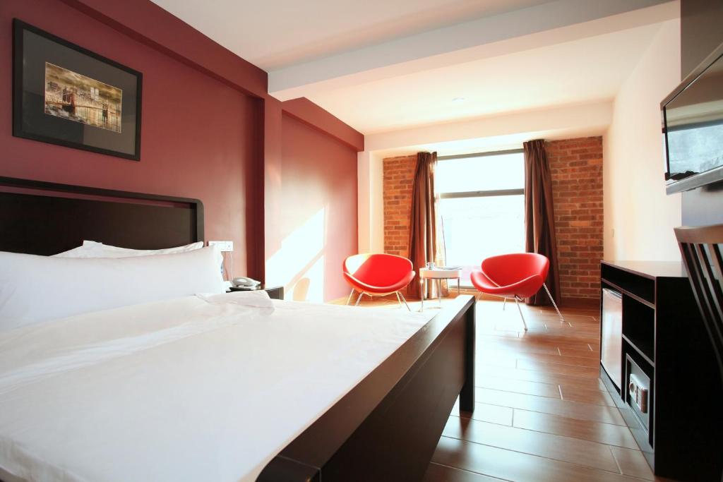 吉隆坡十字路口酒店的酒店客房,配有一张床和两张红色椅子