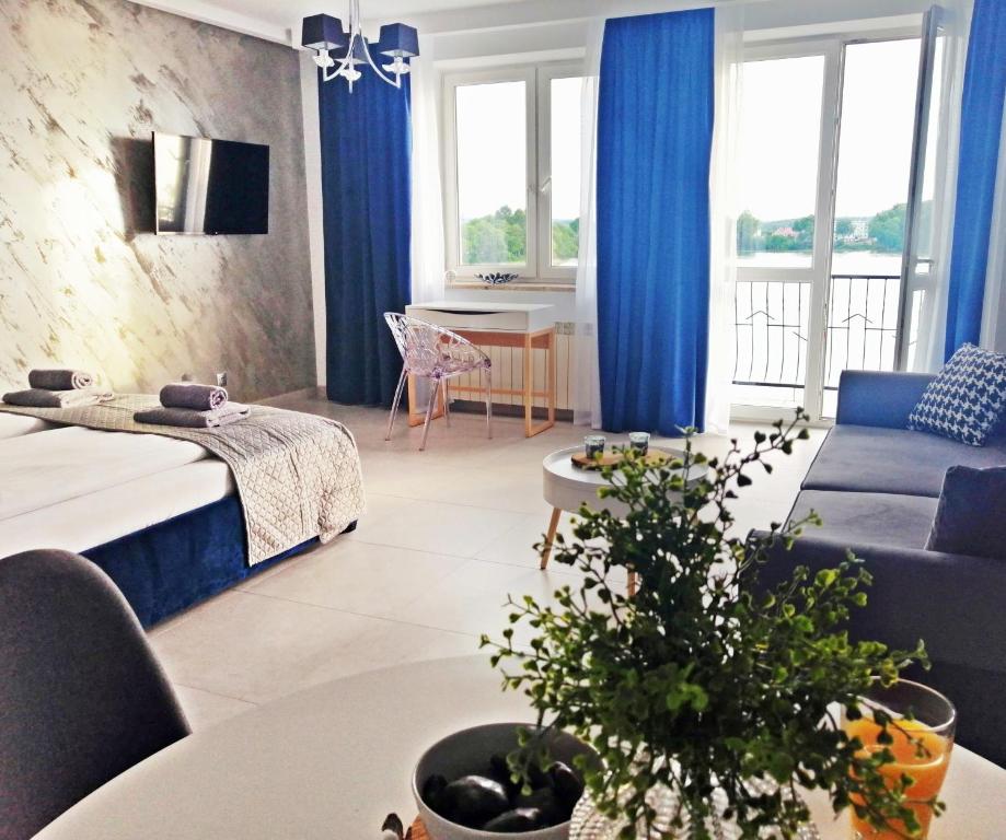 厄尔科Apartamenty Na Skarpie的客厅配有蓝色窗帘、床和桌子