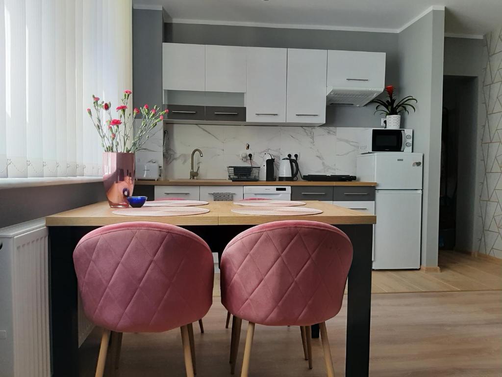 尤斯托尼莫斯基Domki i apartamenty w Ustroniu Morskim的厨房配有桌子和2把粉红色的椅子