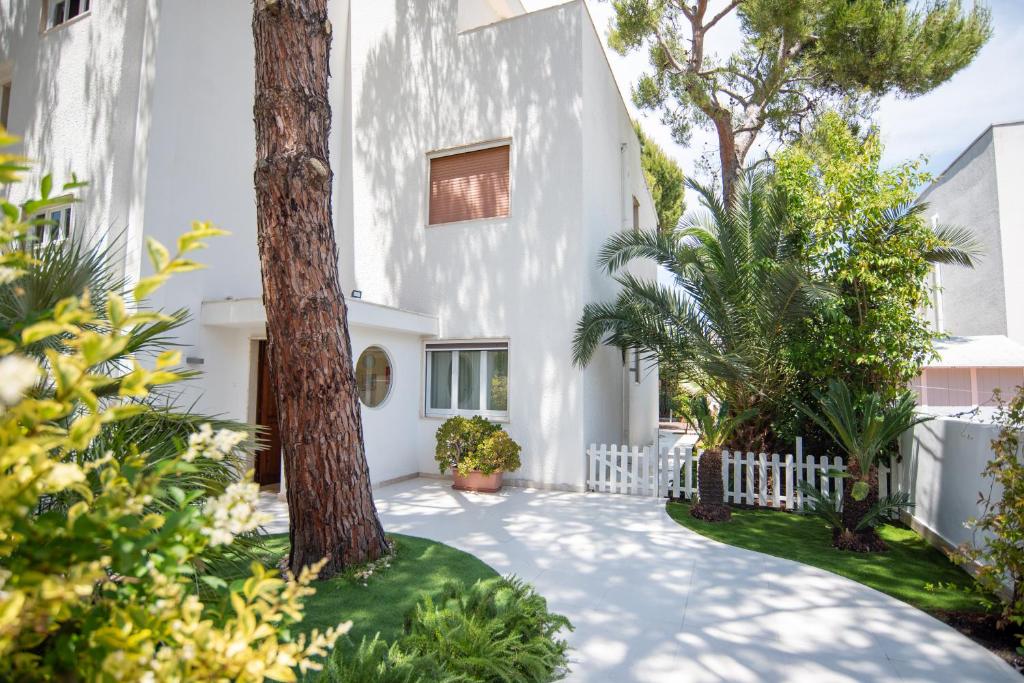 焦维纳佐Blu Sun Apartment in Complesso Riva del Sole的院子里有树的白色房子