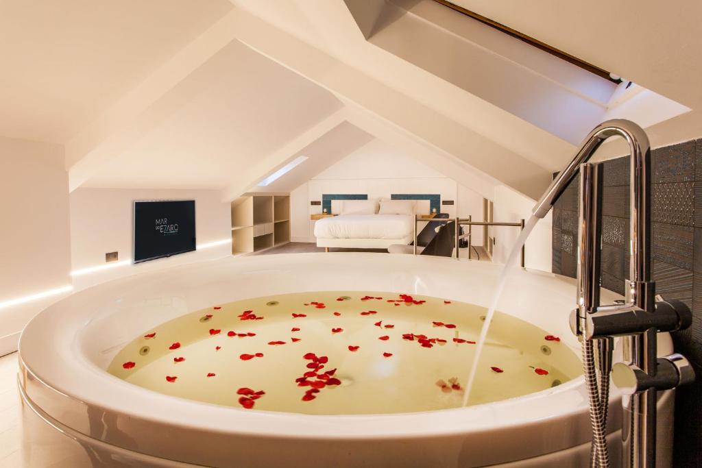 伊扎洛Mar do Ézaro - Boutique Hotel的浴室配有带鲜花的浴缸,位于地板上