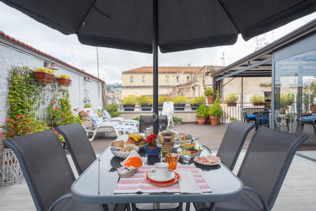 那不勒斯La Terrazza ai Miracoli的露台上的餐桌和食物,配有雨伞