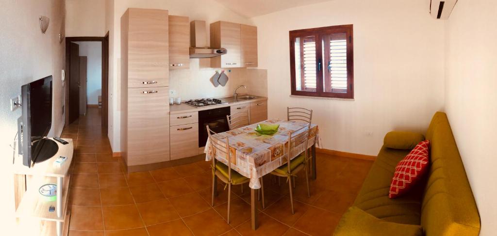 西尼斯科拉Siniscola Casa vacanze Olmo的厨房以及带桌子和沙发的用餐室。