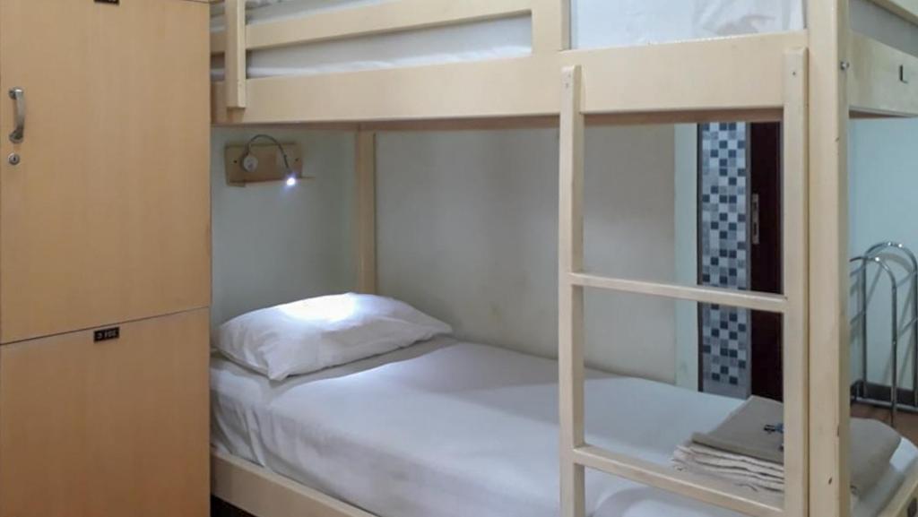 美娜多RedDoorz Hostel @ Manado Green Hostel的卧室配有带白色床的双层床