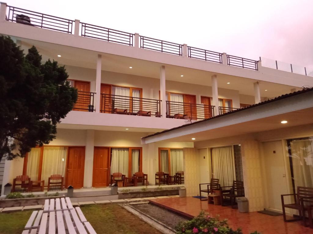 塔旺曼谷Hotel Pondok Asri Tawangmangu的带阳台和桌椅的建筑