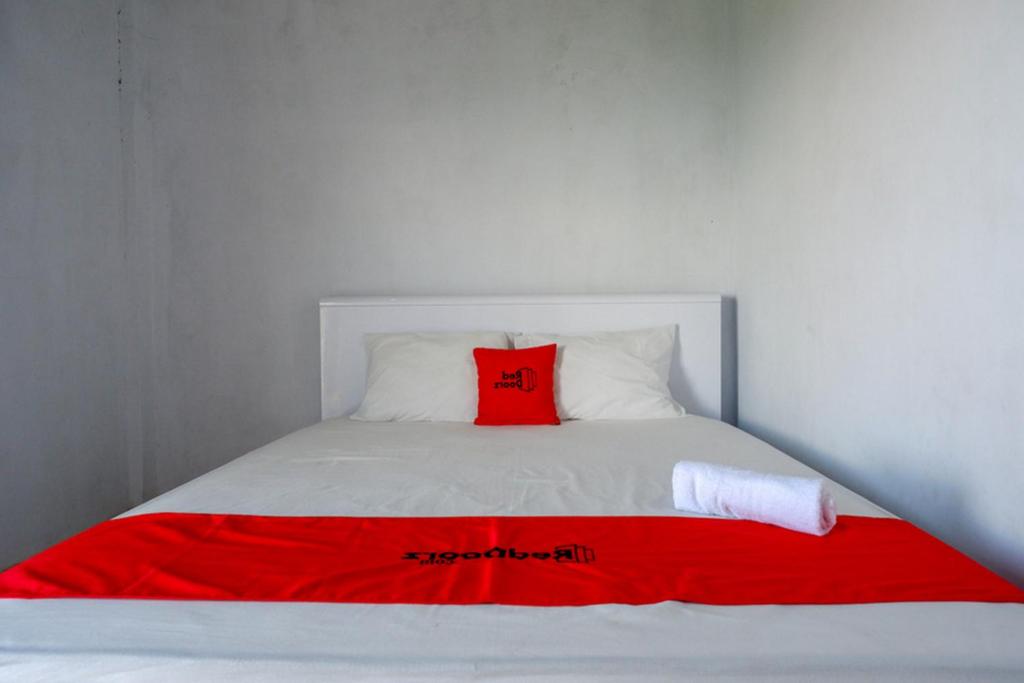 兰特包RedDoorz At Rantepao Toraja Utara的一张白色的床,上面有红色枕头