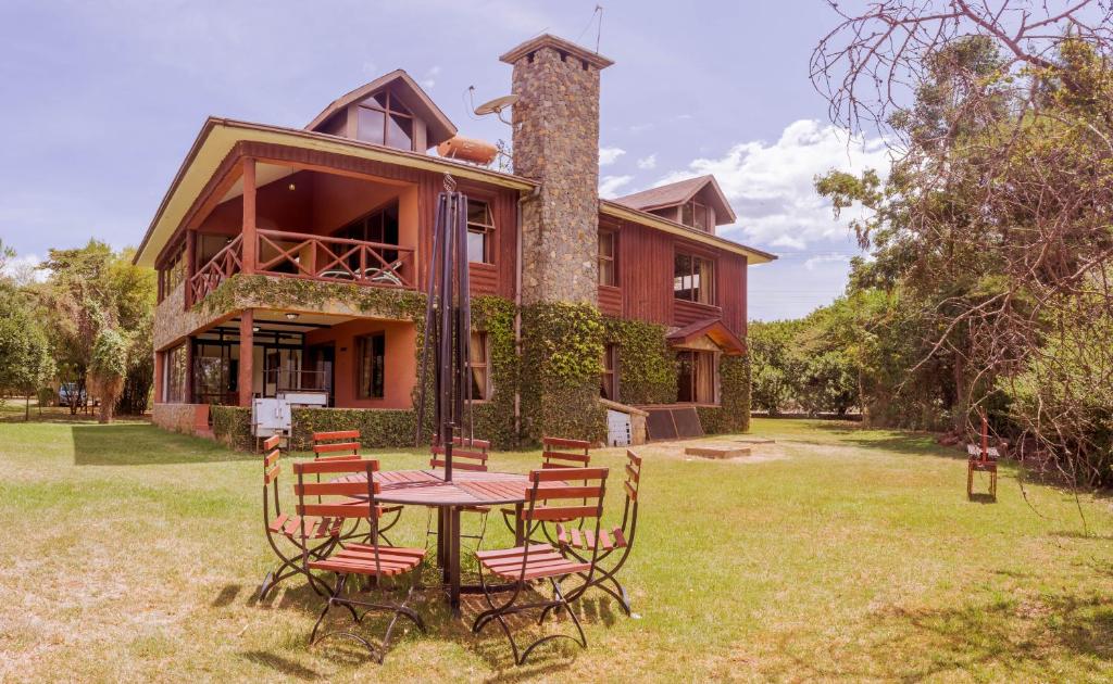 奈瓦沙Ol-Kine Cottage at The Great Rift Valley Lodge & Golf Resort Naivasha的房子前面的一张桌子和椅子