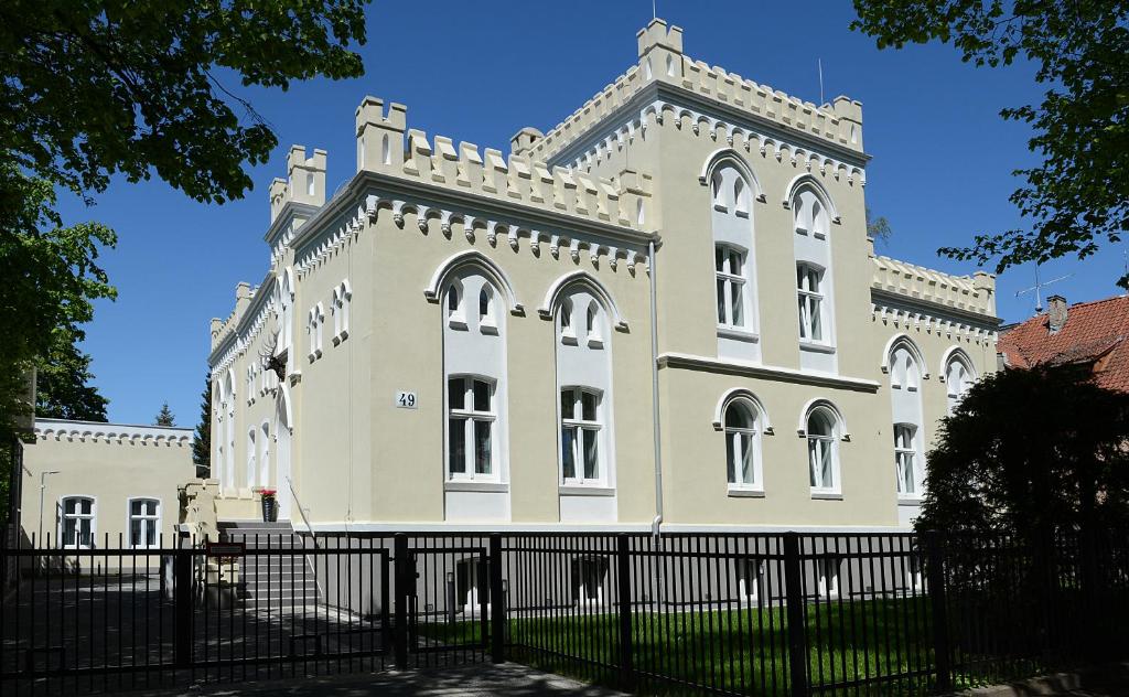 科沙林Rezydencja Myśliwska - Apartamenty的前面有栅栏的大建筑