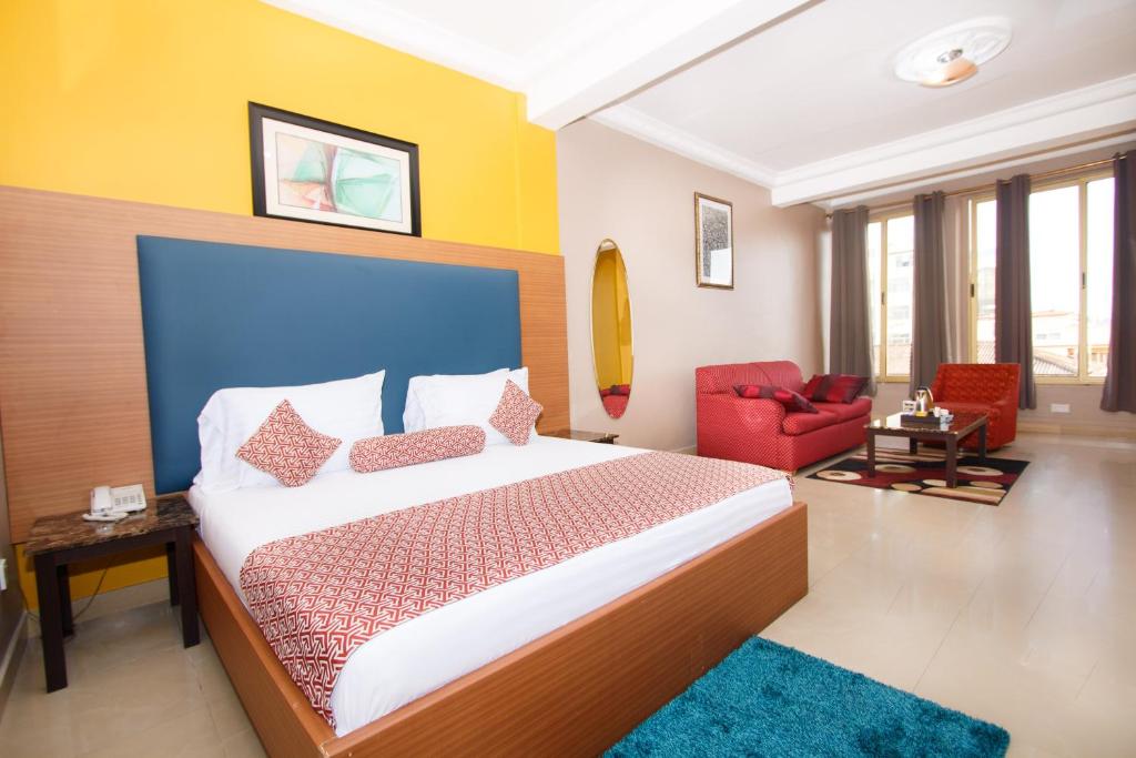 阿克拉Prestige Suites的一间卧室配有一张大床和一张红色椅子
