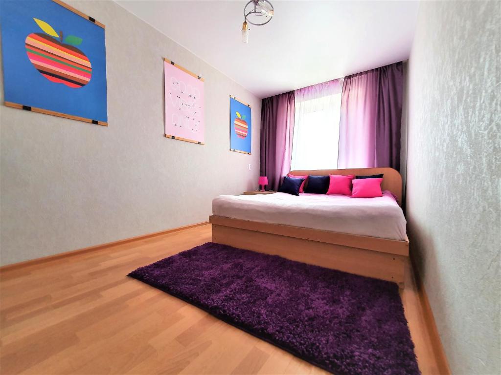 沃罗涅什MEGAPOLIS улица Карла Маркса 76-42的一间卧室配有一张带紫色地毯和窗户的床