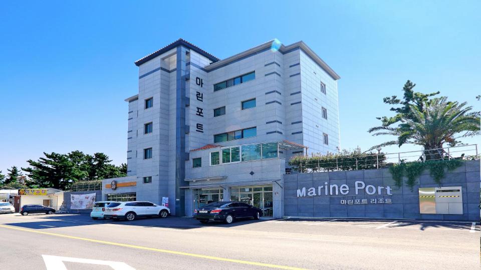 西归浦市海运港口度假酒店的白色的建筑,有汽车停在停车场