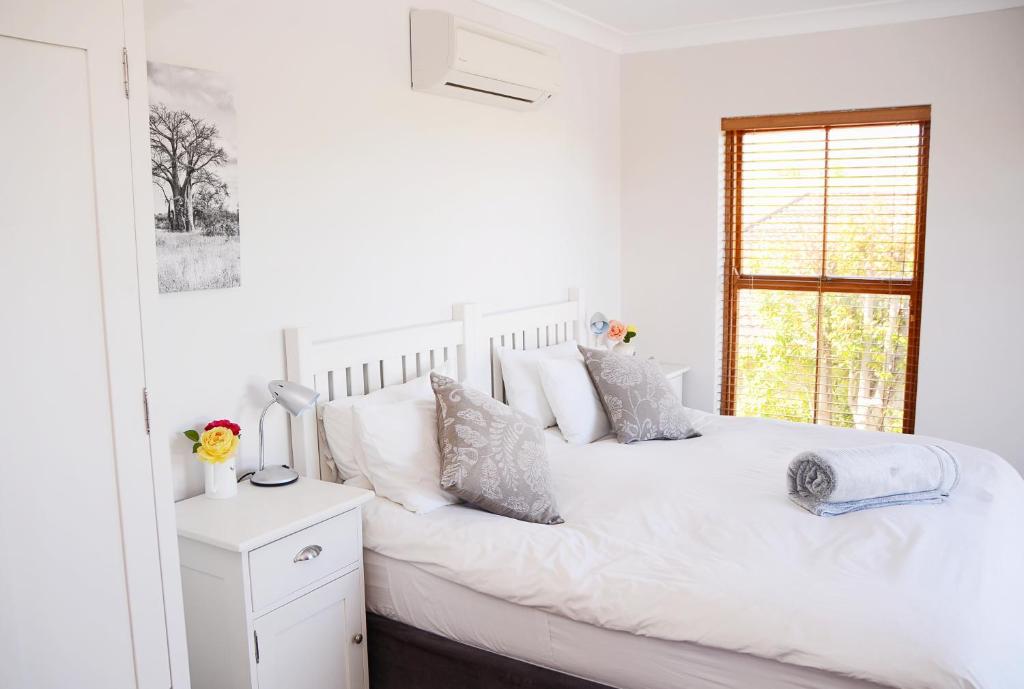 斯泰伦博斯Penelope's Stellenbosch的白色的卧室设有白色的床和窗户。