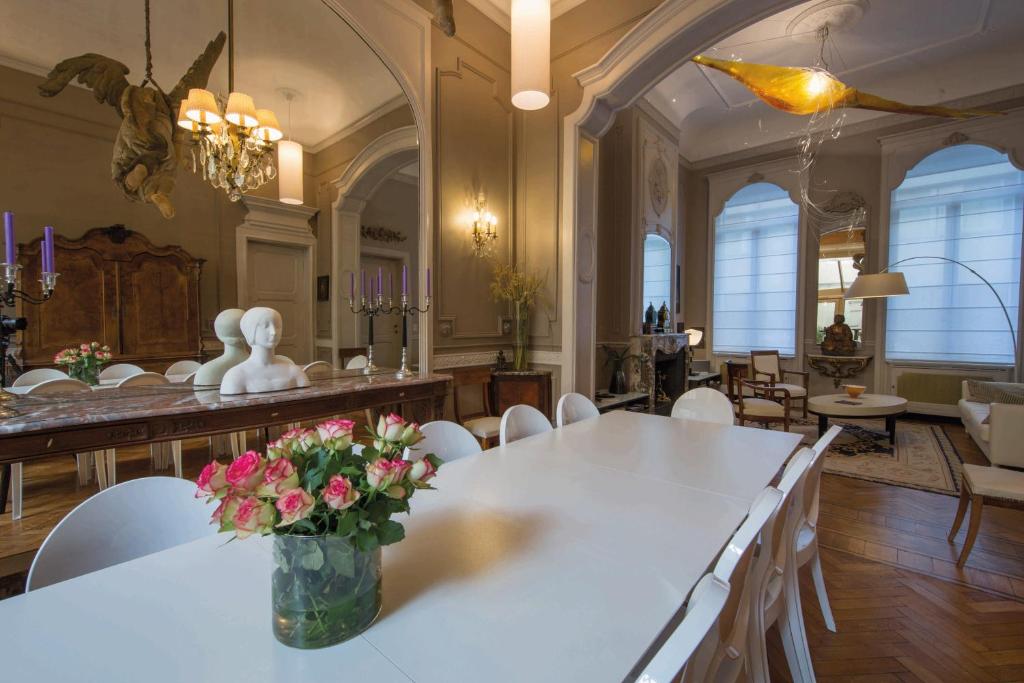 布鲁塞尔路易庭院住宿加早餐旅馆的用餐室配有带鲜花的白色桌子