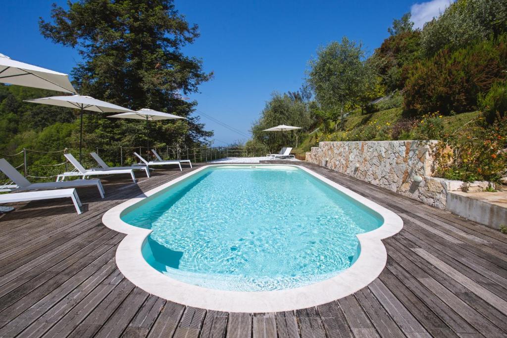 卡麦奥雷Villa Borgovecchio B&B的木制甲板上配有椅子和遮阳伞的游泳池