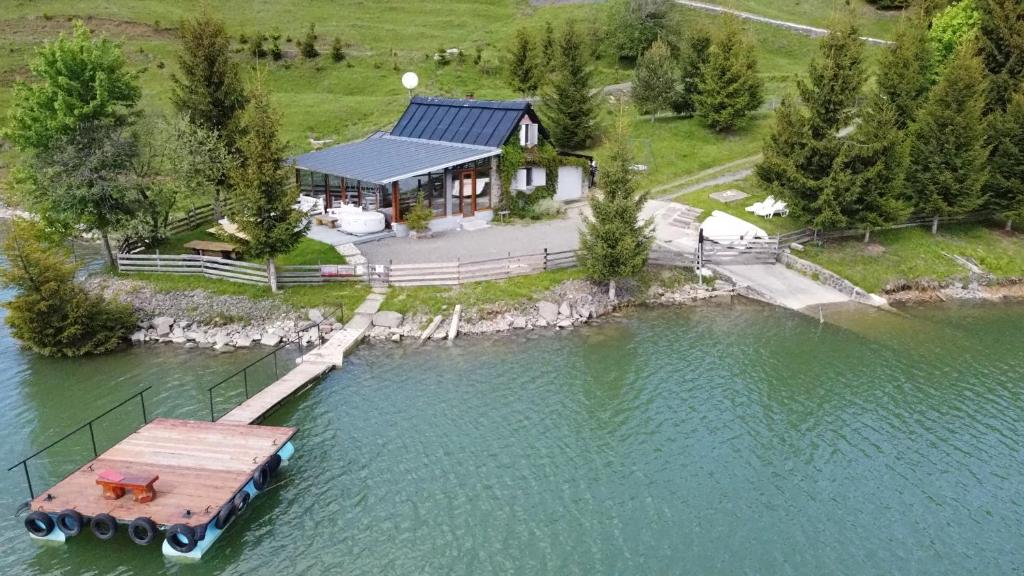 科利比塔Traditional Casa Pescarului langa lac cu ponton的水面上房屋的空中景观,带码头