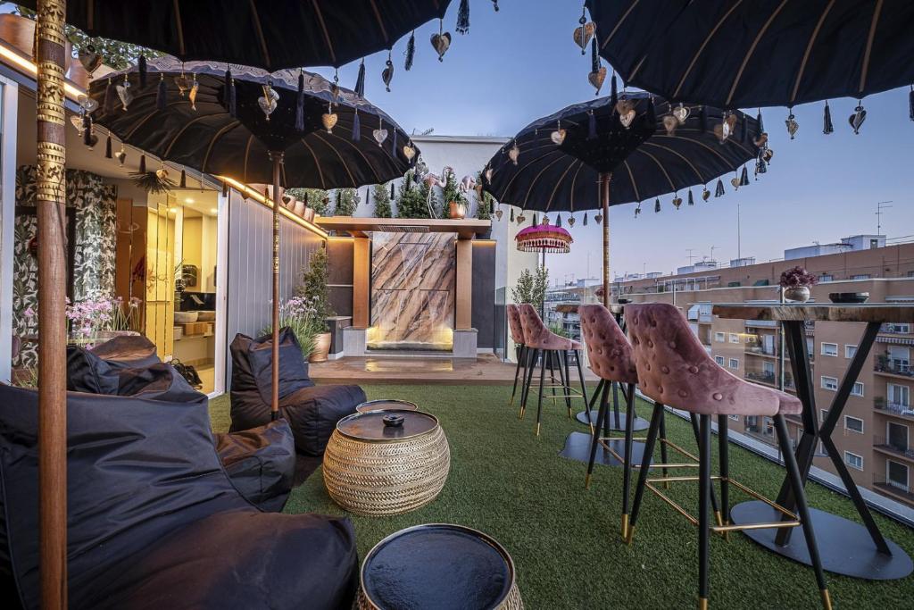 塞维利亚ON Suites Sevilla Apartments designed for adults的屋顶上带椅子和遮阳伞的天井