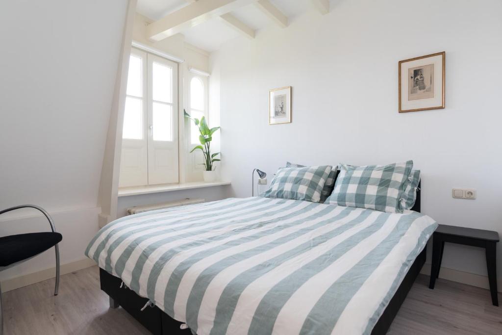 阿姆斯特丹Central Rooftop Terrace Guest Suite的白色卧室,配有带条纹毯子的床
