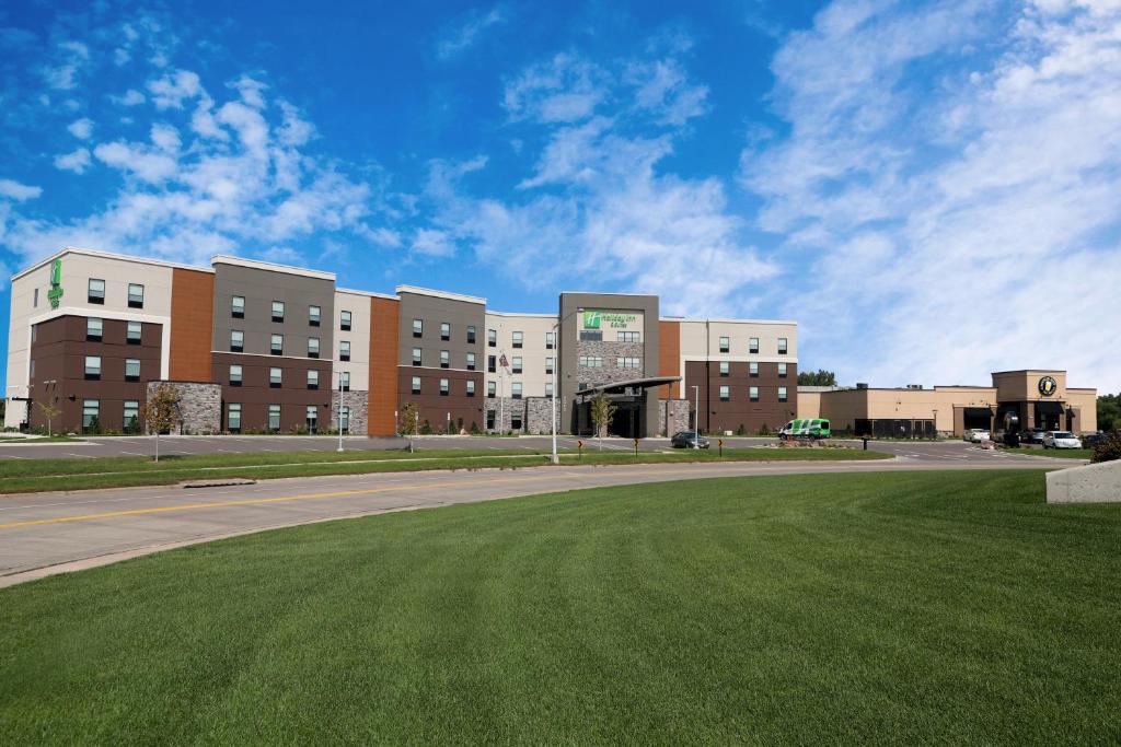 苏福尔斯Holiday Inn & Suites Sioux Falls - Airport, an IHG Hotel的前面有草地的大建筑